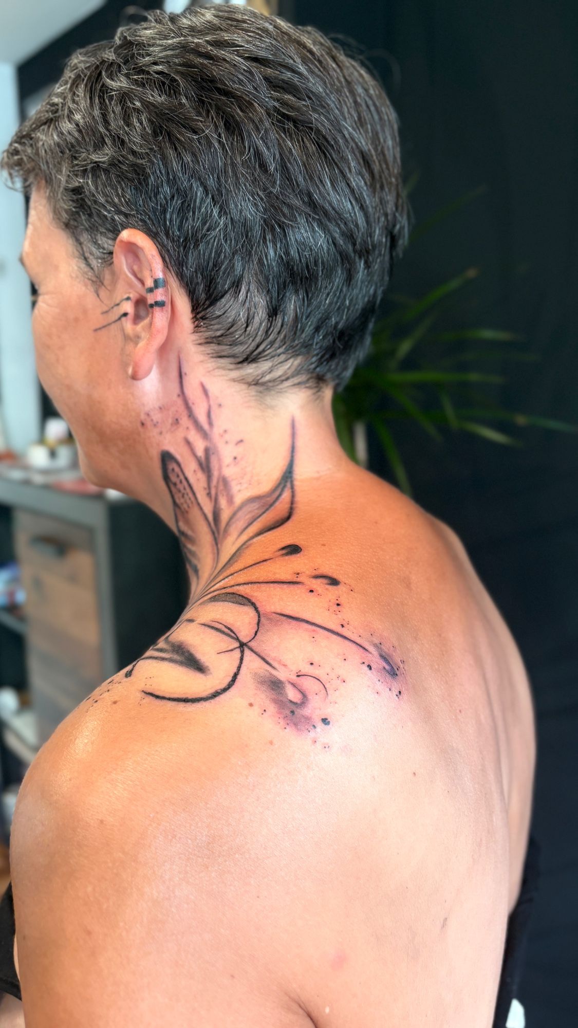 Abstrakte Blume am Hals, sowie BLKWRK Ohr im Blackwork Style auf Hals von Anne Riot Tattoo in Hamburg