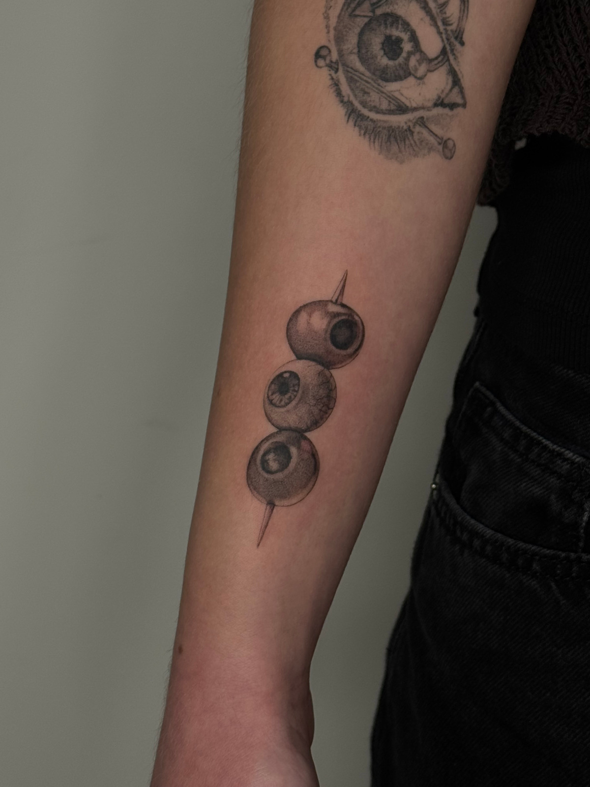 Augenschmaus Wanna Do 🫒 im Black & Gray Style auf Unterarm von launau.tattoo in Leipzig