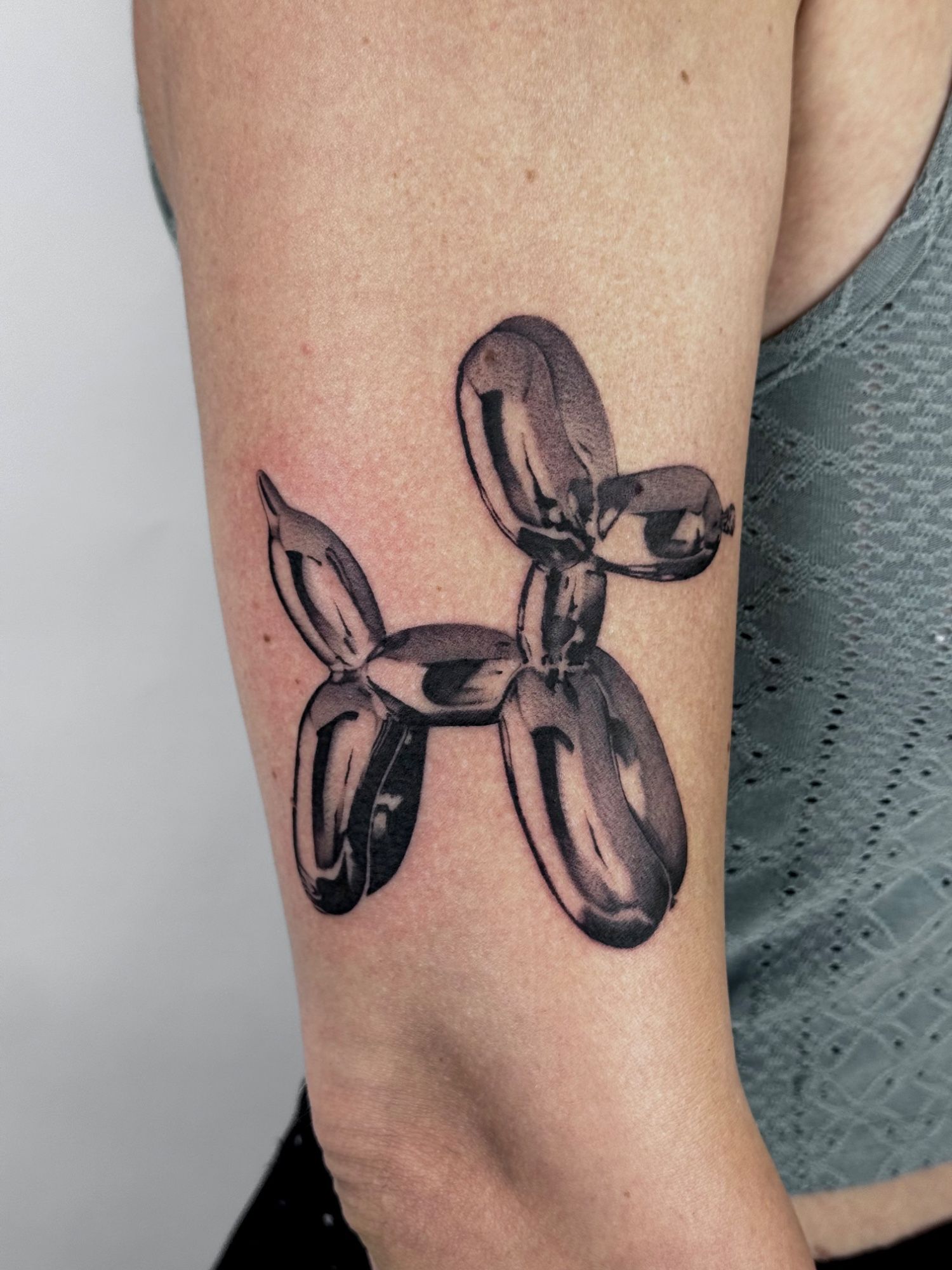 Chrome Balloon Dog Wanna Do im Black & Gray Style auf Oberarm von launau.tattoo in Leipzig