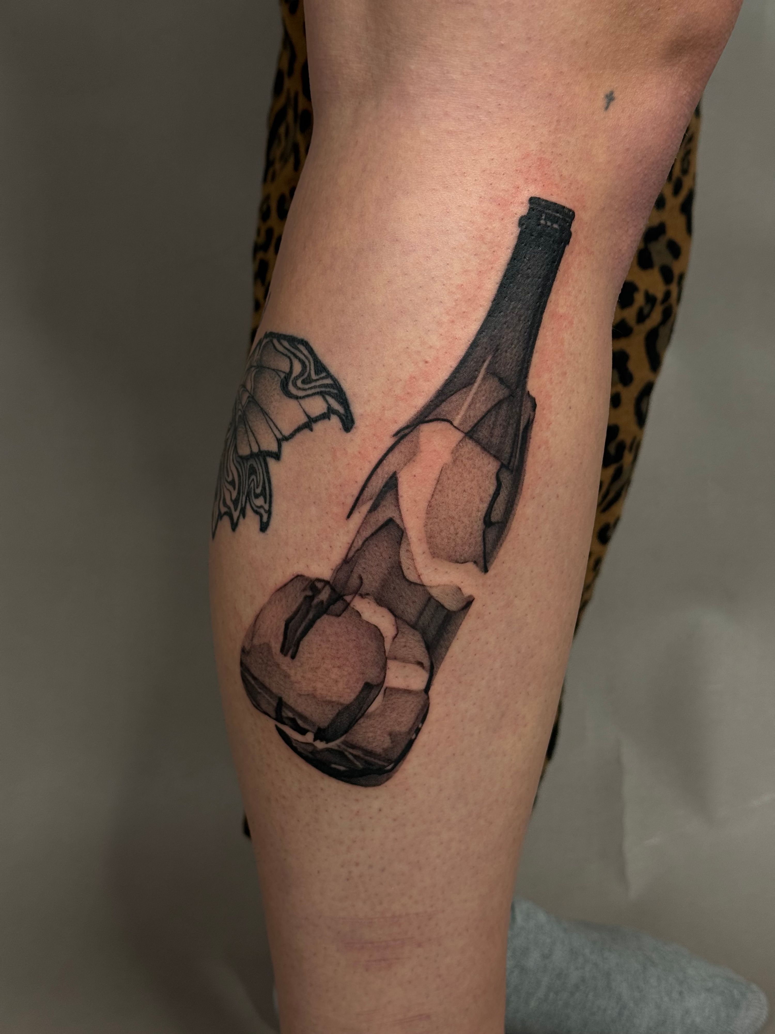 Broken Bottle Wanna Do im Surrealismus Style auf Bein von launau.tattoo in Leipzig