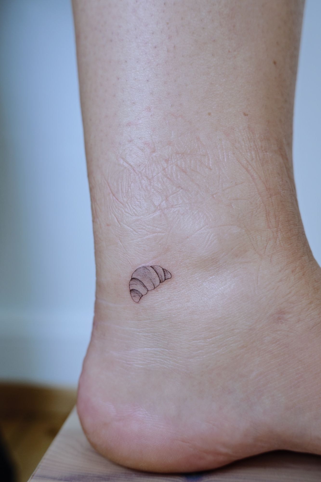 Mini Croissant in Fineline style on Ankle by @alinaatattoo 20457