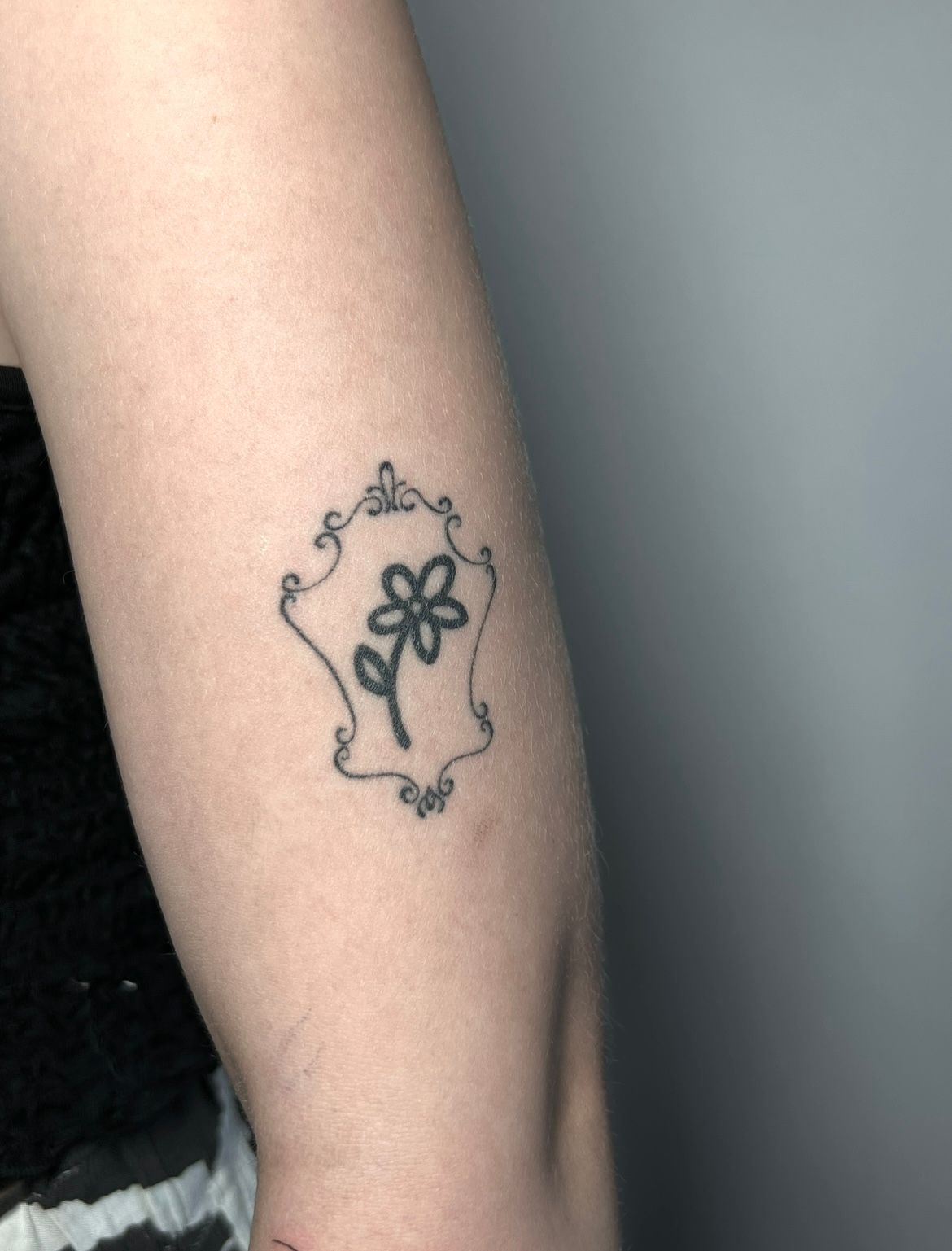 Gerahmte Blume auf dem Oberarm im Blackwork Style von Morwen in 49074