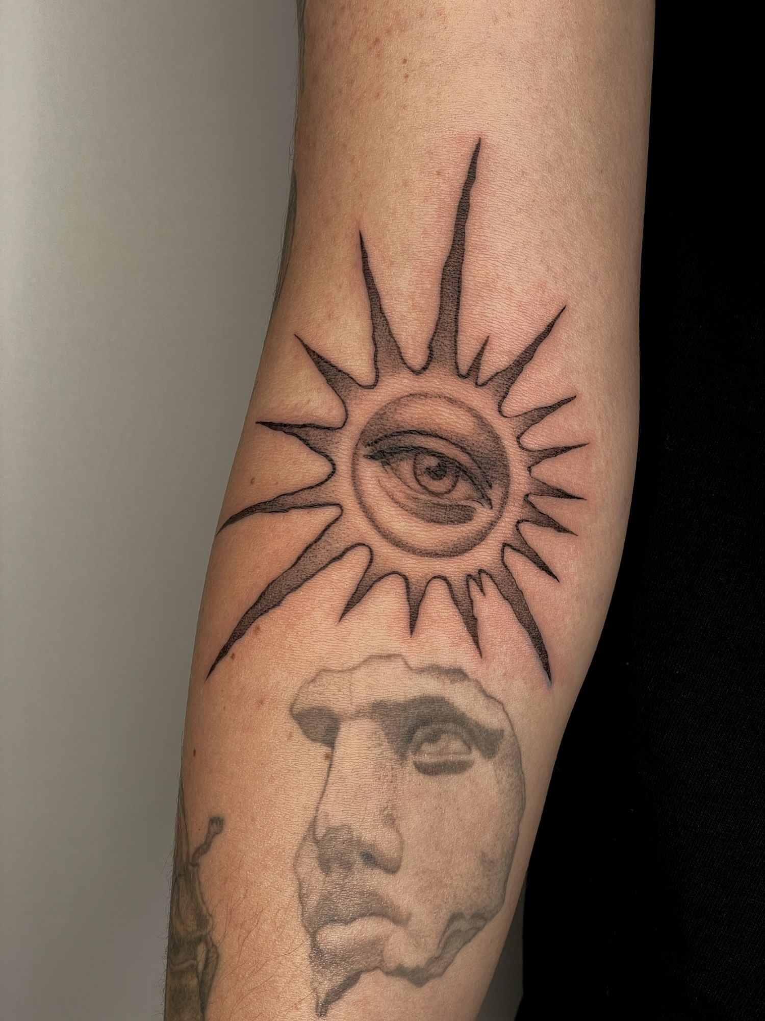 Surrealistische Sonne mit Auge Armbeuge im Blackwork Style auf Unterarm von Pretty Bold in Hamburg