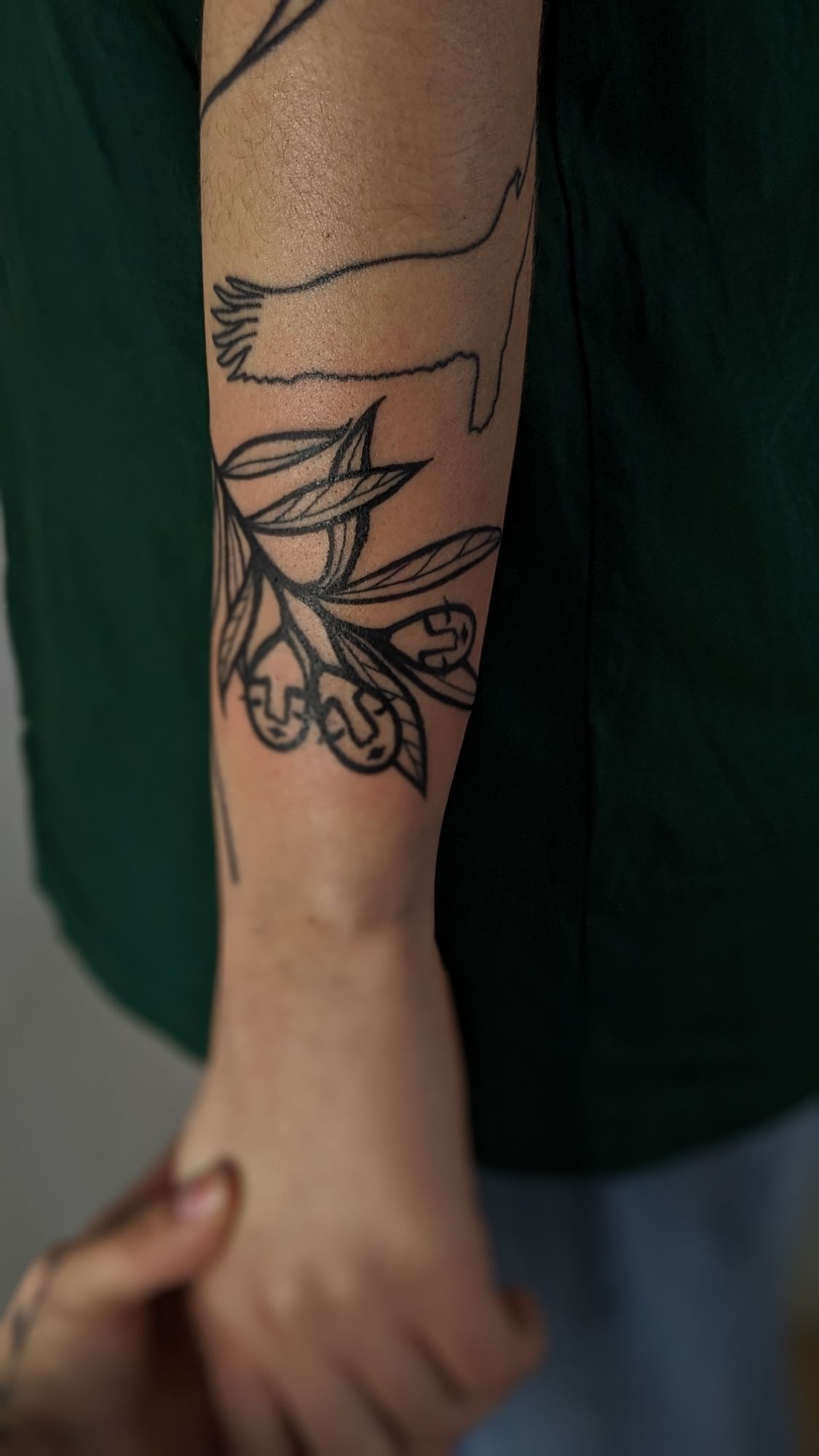 olive x janus Gesicht signature in Blackwork style on Forearm by janus_tattoo Hamburg