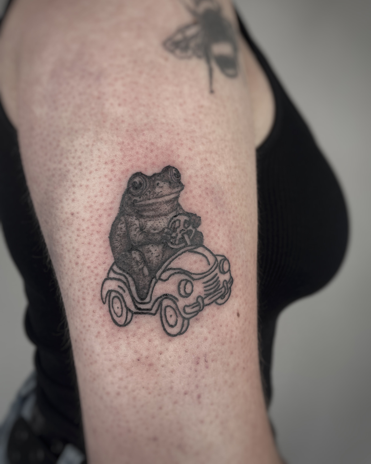 Frosch in Auto im Microrealistic Style auf Oberarm von mansiehtsichmal.tattooo Leipzig