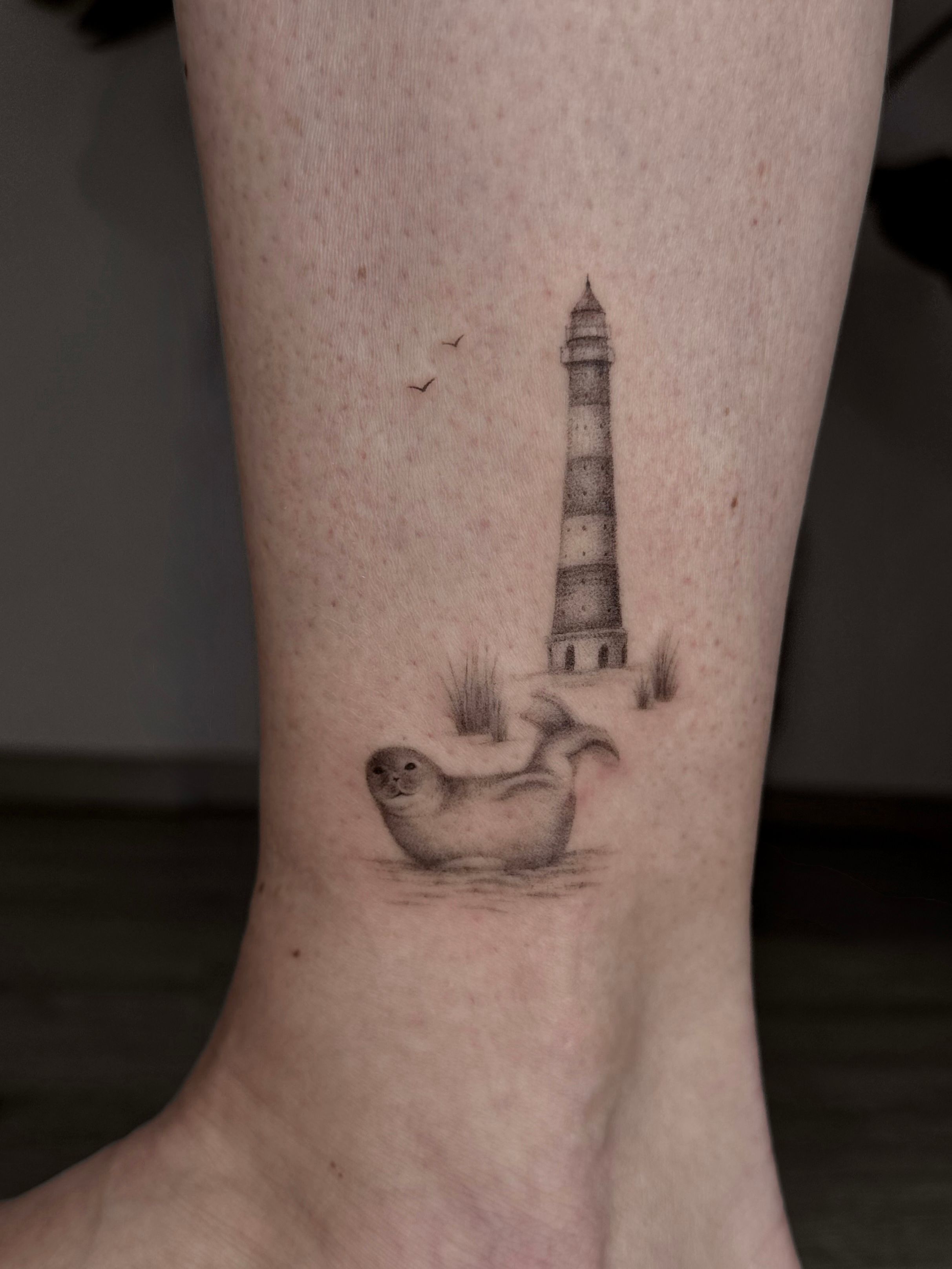 Robbe mit Leuchtturm in Fineline style on Leg by Room 23 tattoo & art Lübeck