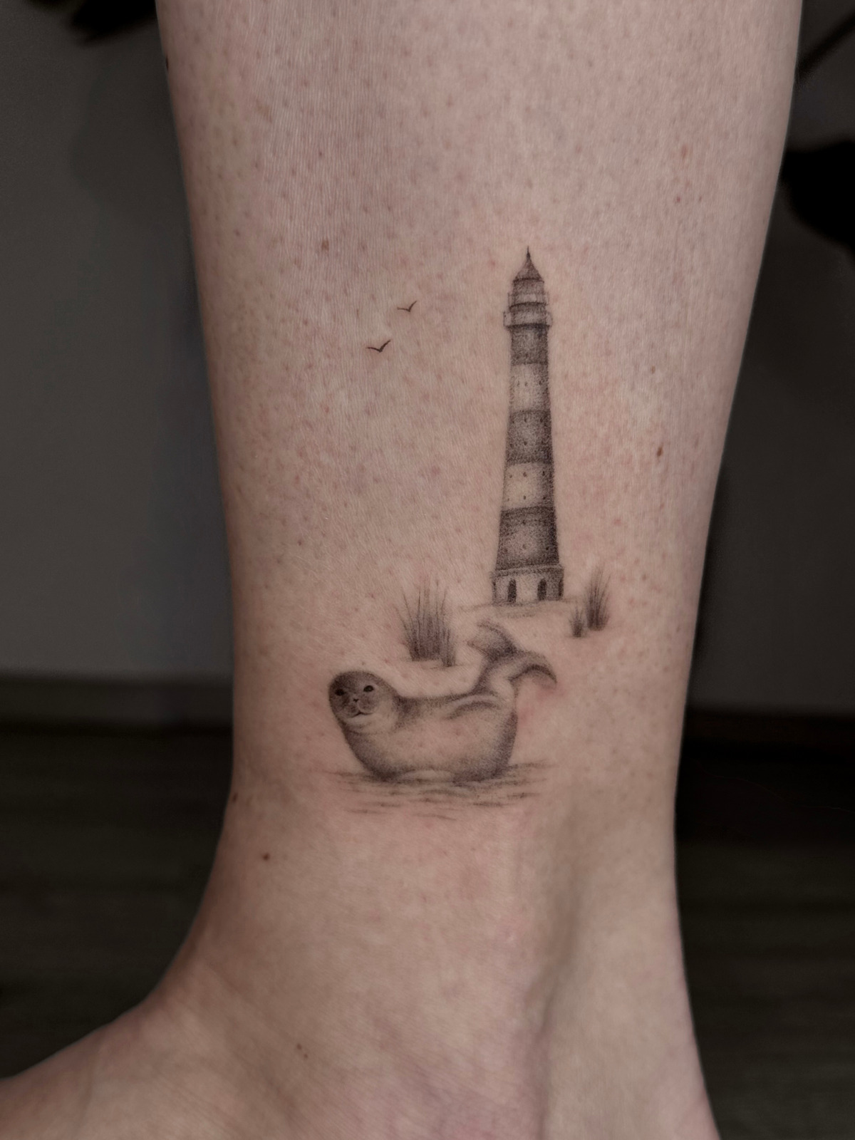 Robbe mit Leuchtturm in Fineline style on Leg by Ivy Art Lübeck