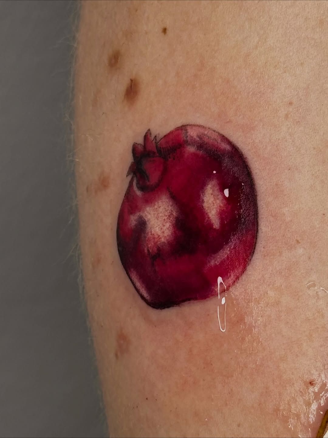 Granatapfel Realistische Oberarm-Tattoo im Realistic Style auf Oberarm von kaleriiaa tattoo in Lübeck