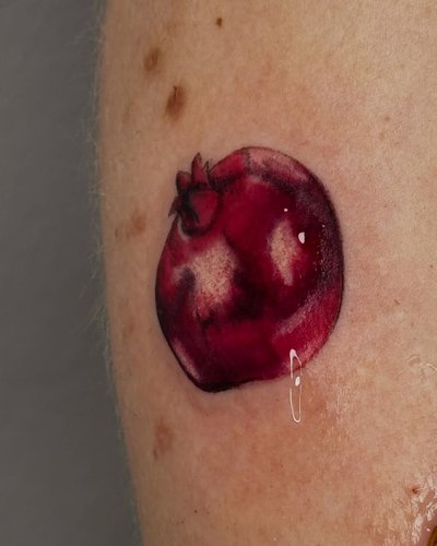 Granatapfel Realistische Oberarm-Tattoo im Realistic Style auf Oberarm von kaleriiaa tattoo in Lübeck