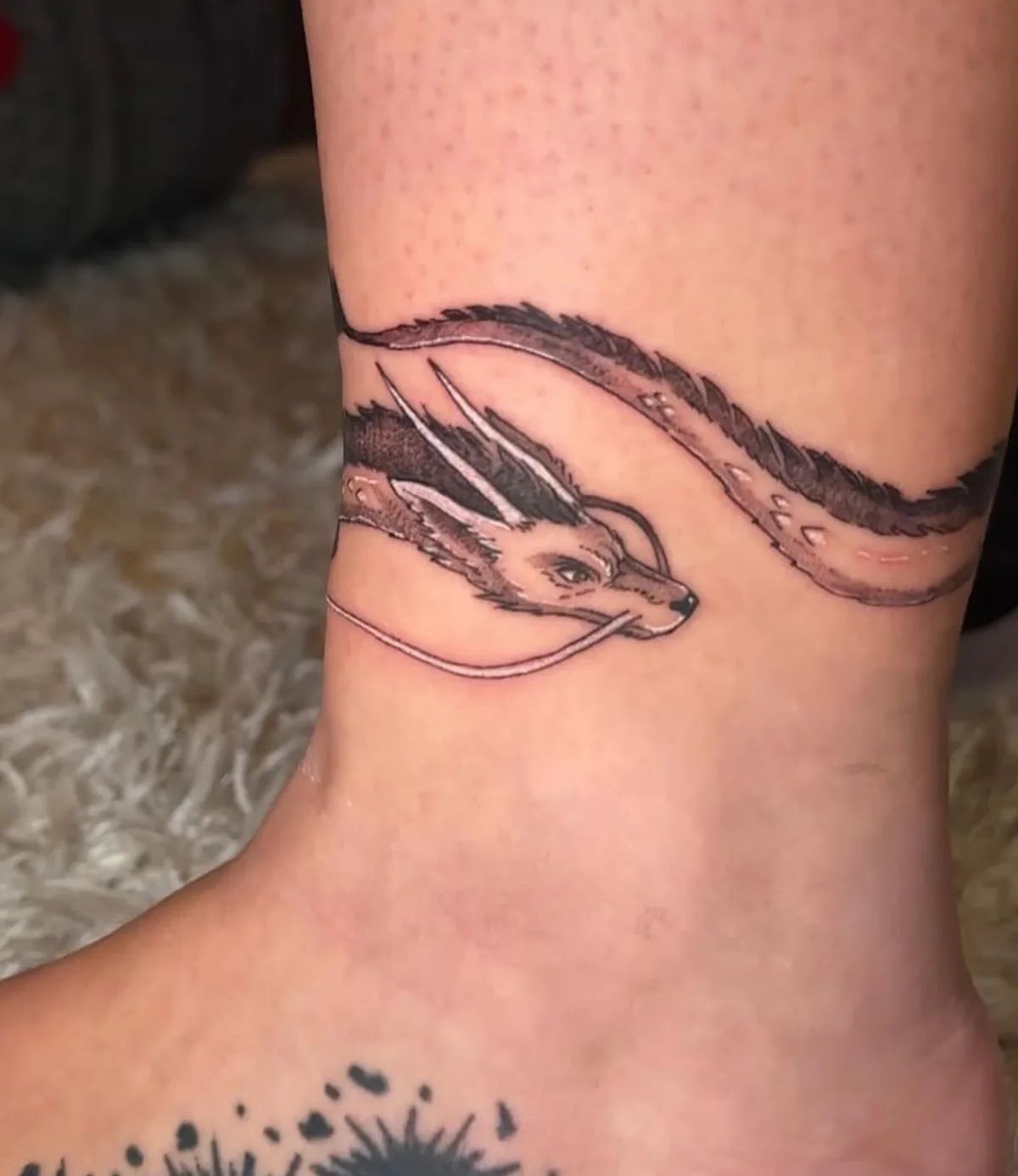 Dragon armring tattoo in fine line style on ankle