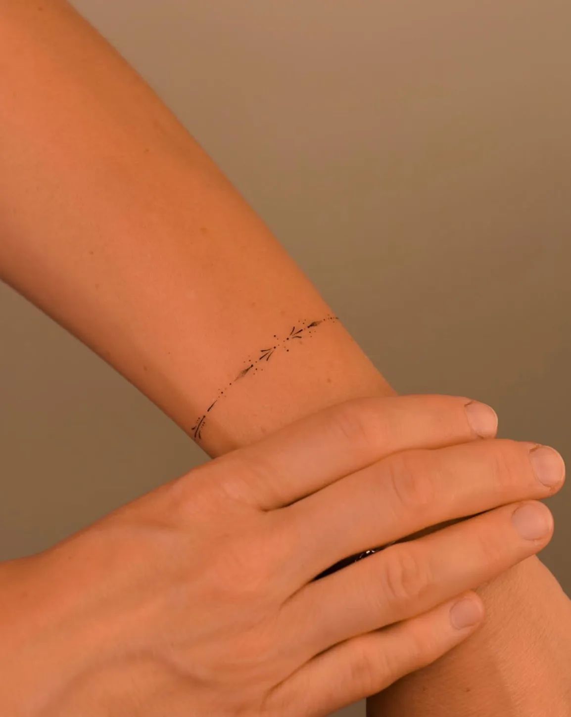 Delicate fine line armring tattoo on the forearm