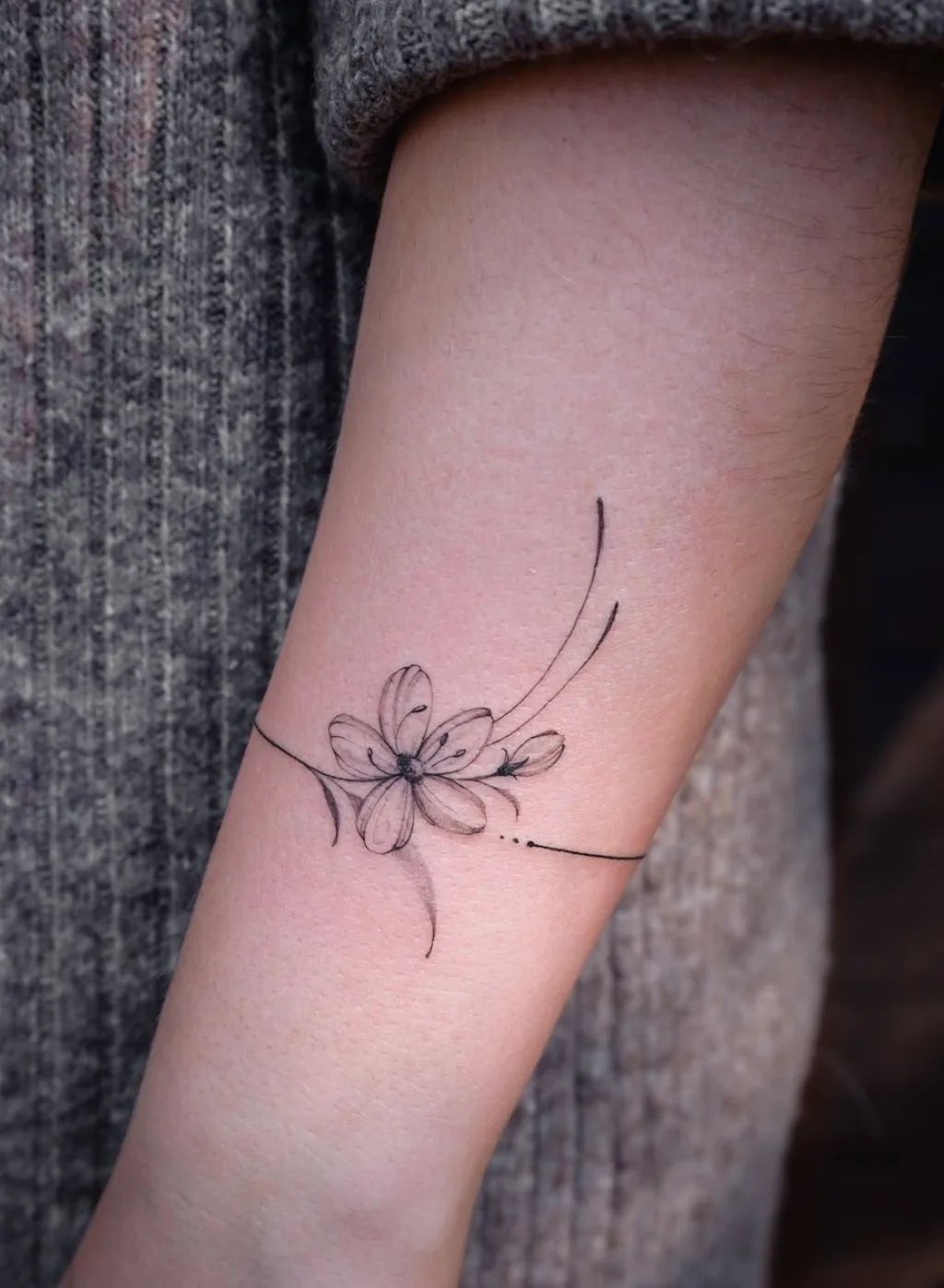 Fine line armring tattoo with floral motif on the forearm