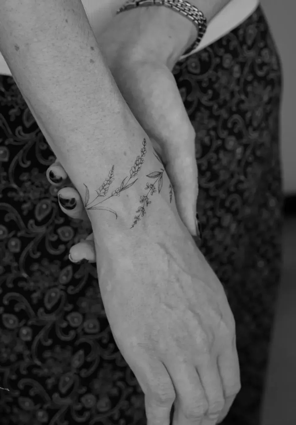 Delicate lavender tattoo in fine line style on the wrist, designed as an armring