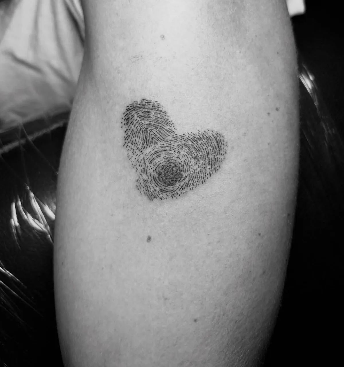 Heart tattoo made of fingerprints in fine line style on upper arm