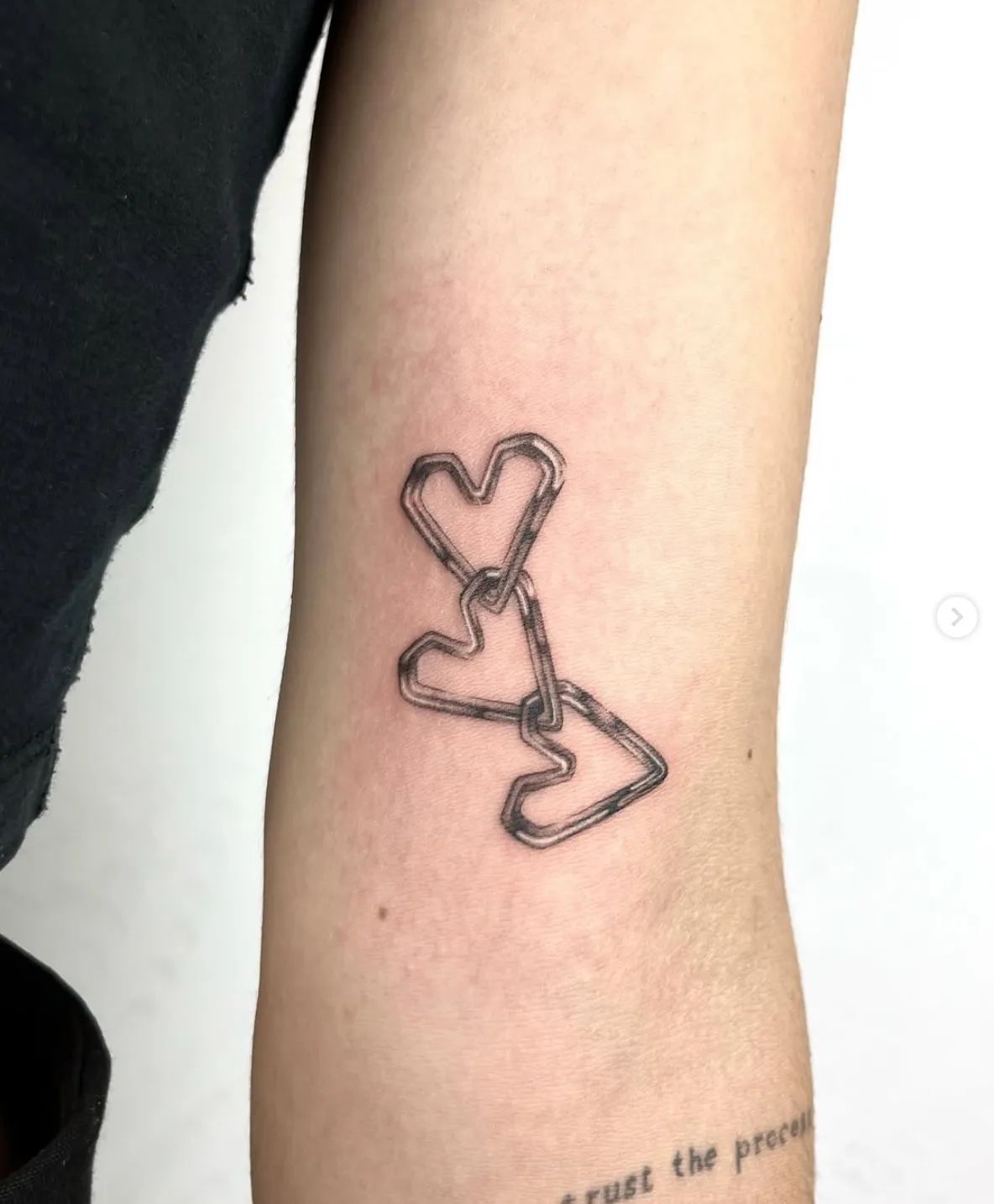 Small hearts chain fine line tattoo on upper arm by Maria Schwuchow