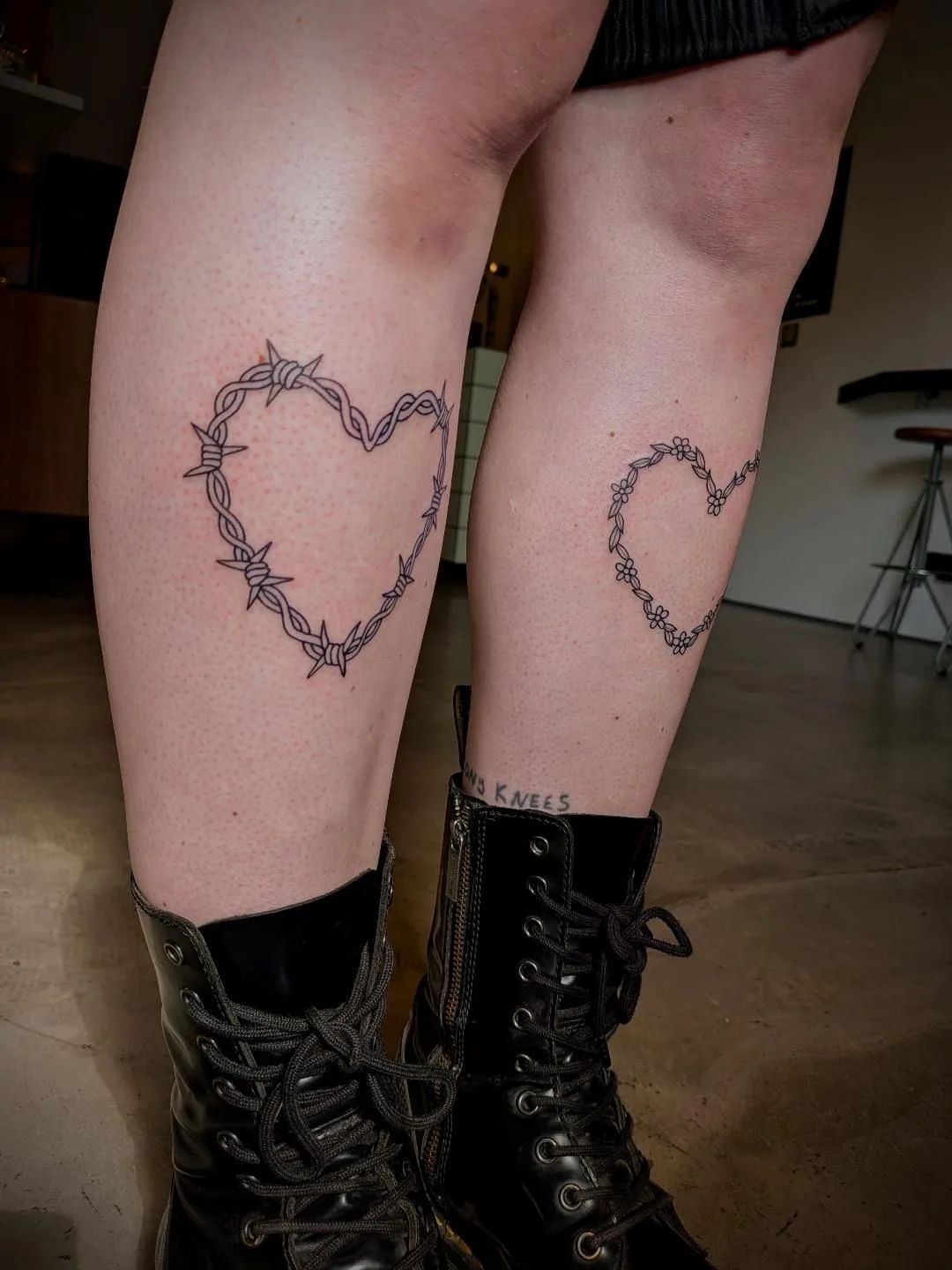 Barbed wire heart and floral vine heart tattoos on calves