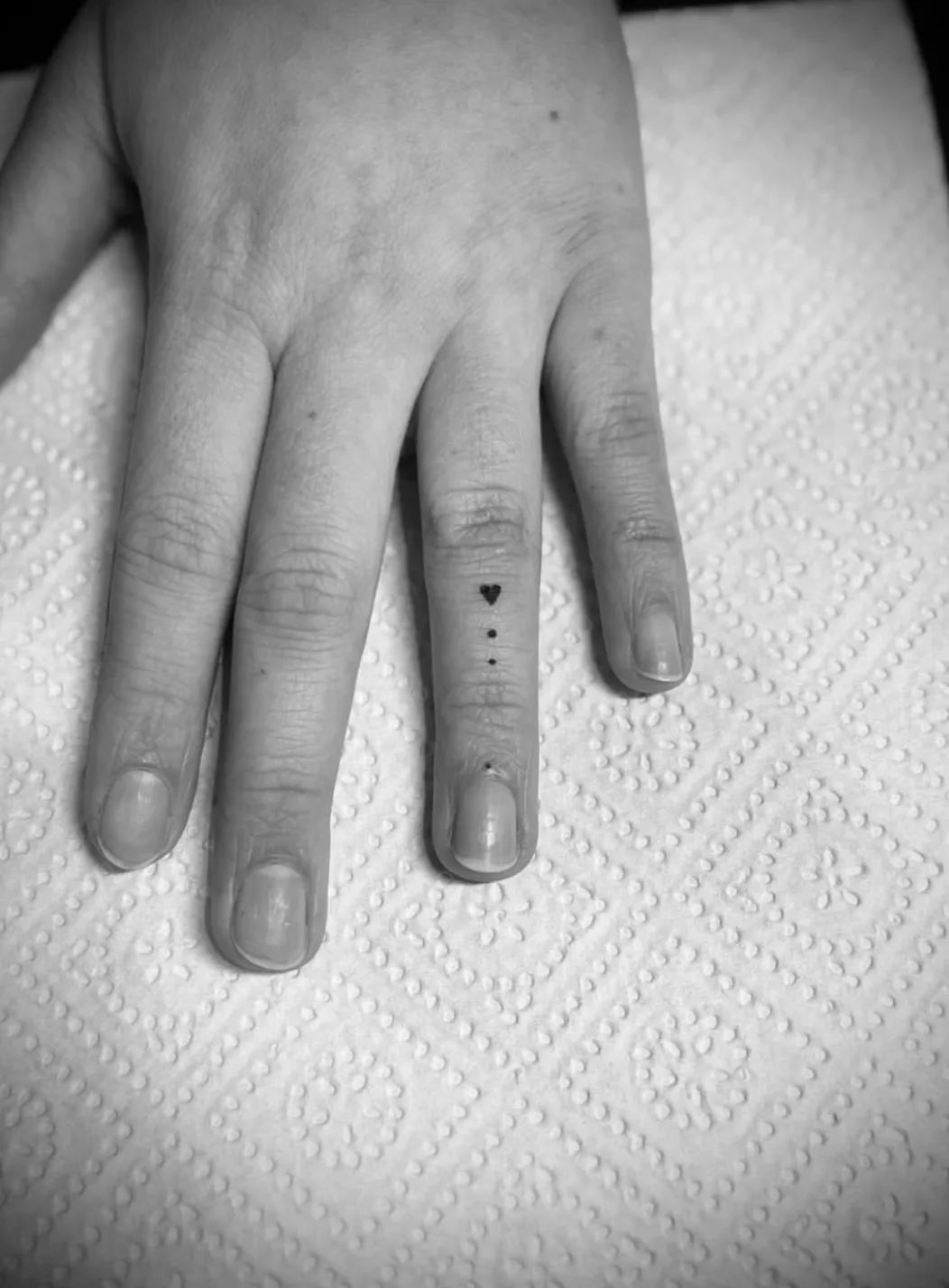 Small heart and three dots fine line tattoo on finger