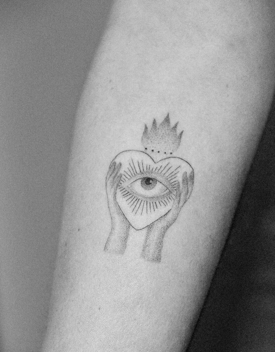 Heart tattoo with eye and hands in dotwork style on upper arm