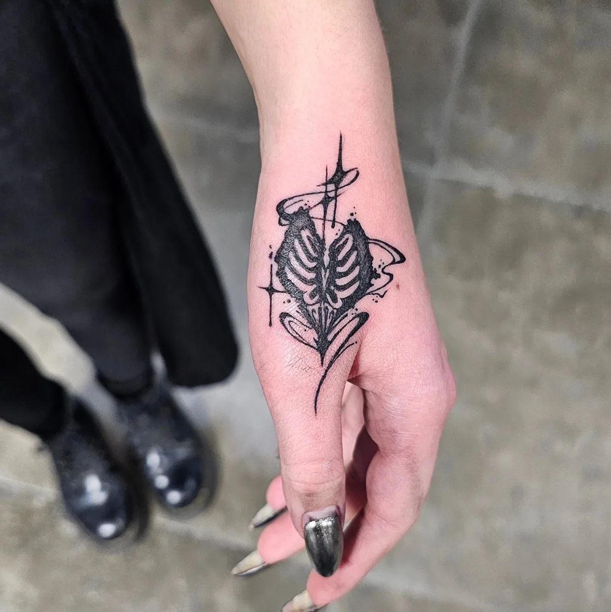 Abstract heart skeleton tattoo in trash polka style on the back of the hand