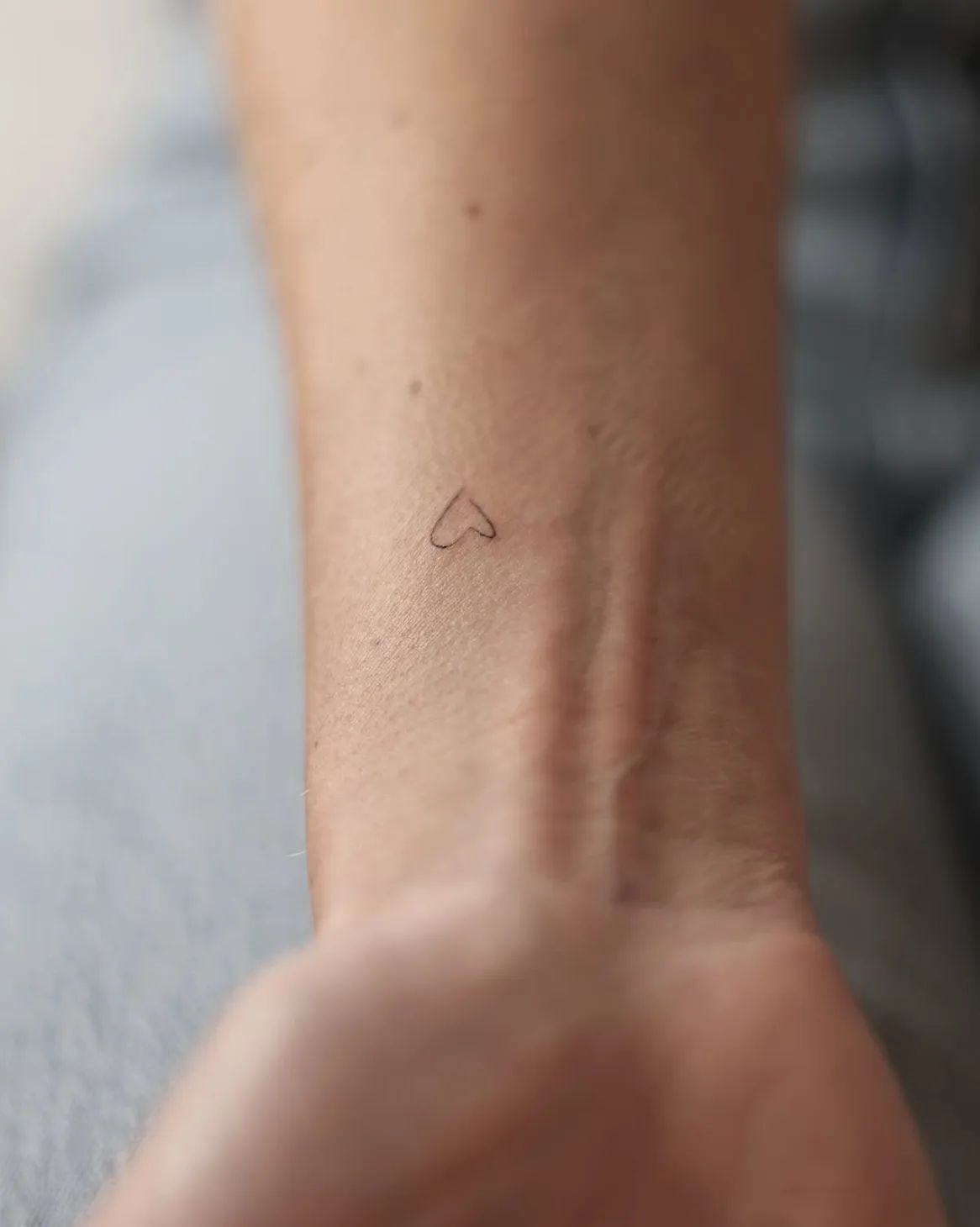 Minimalist heart tattoo as a fine line on the wrist
