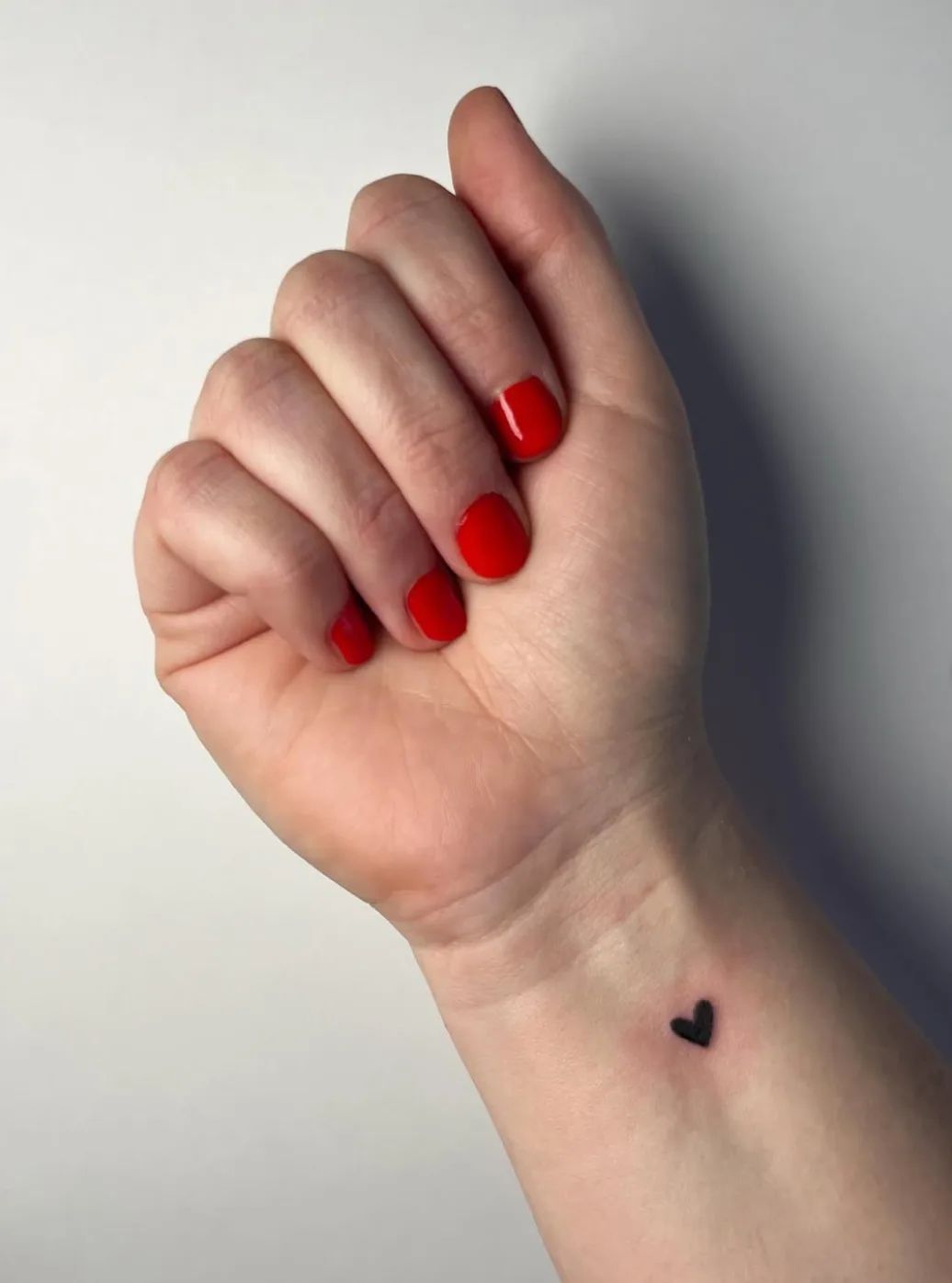 Small black heart tattoo on wrist