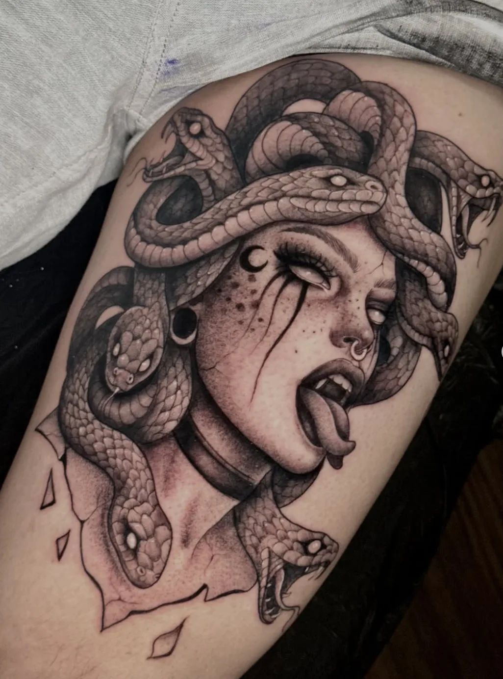 Realistisches Medusa Tattoo mit Schlangen und Zunge herausgestreckt am Oberschenkel