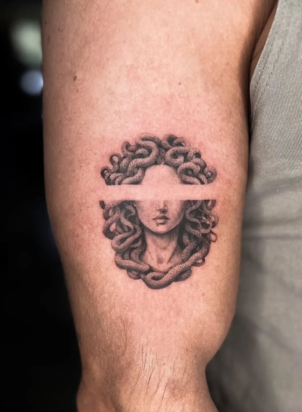 Medusa Tattoo im Fineline-Stil am Oberarm mit horizontaler Lücke