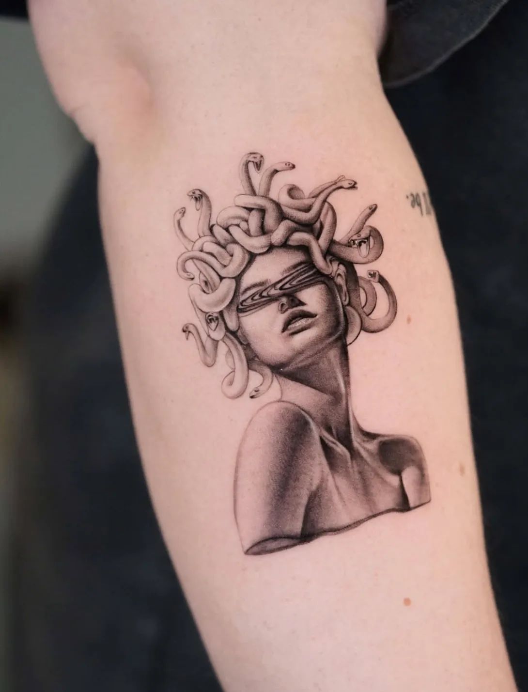 Realistisches Medusa Tattoo mit Schlangenhaaren und verzerrten Augen auf dem Oberarm