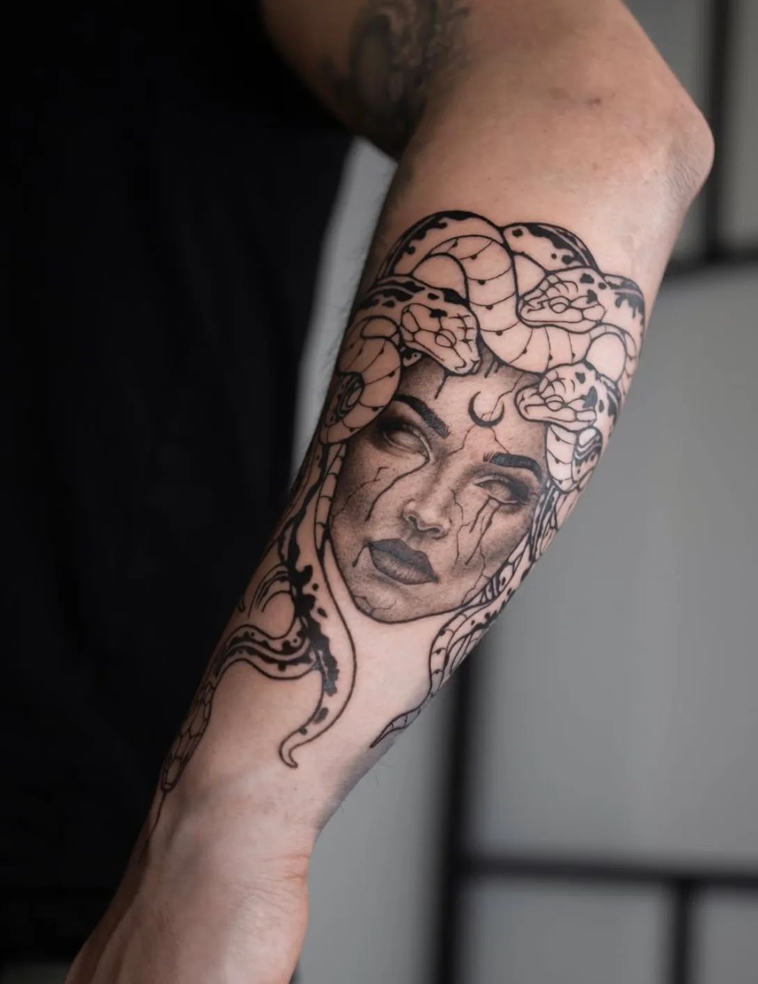 Medusa Tattoo im Blackwork-Stil am Unterarm mit Schlangen und Rissen im Gesicht