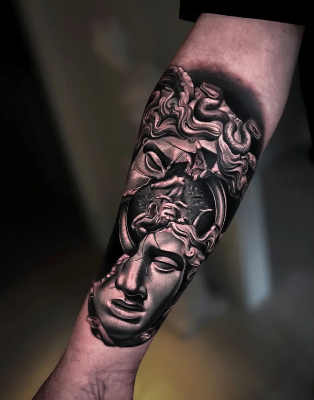 Realistisches Medusa-Tattoo in Schwarz-Grau mit zerbrochener Statue am Unterarm