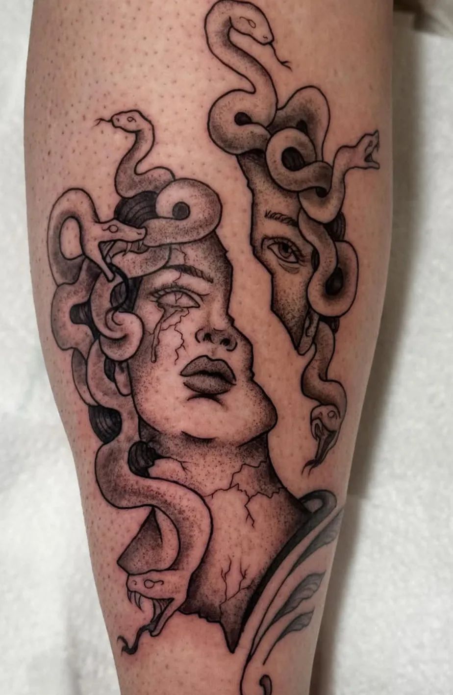 Medusa Tattoo im Dotwork-Stil am Bein, mit gespaltenem Gesicht und Schlangenhaar