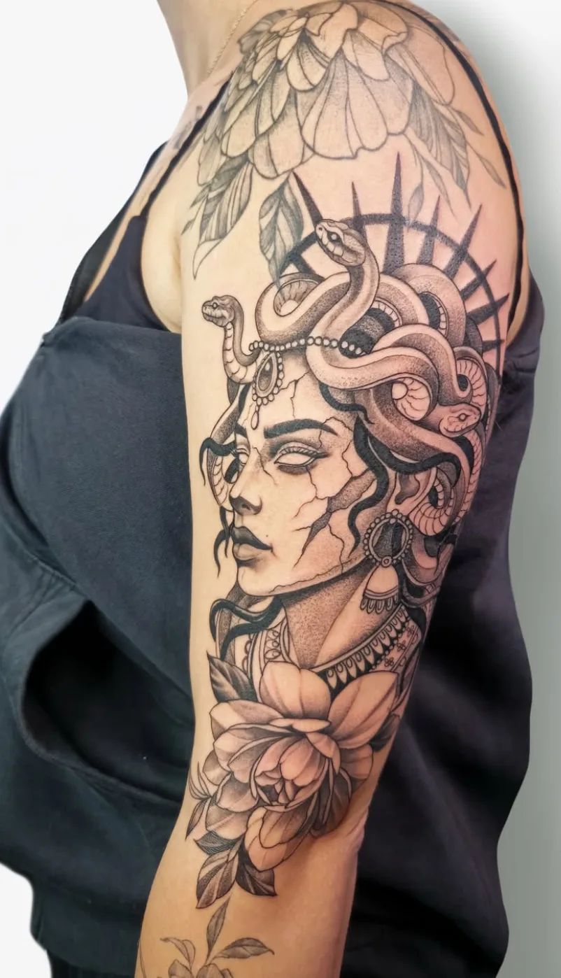 Medusa Tattoo im Blackwork-Stil mit Schlangen und Blumen am Oberarm
