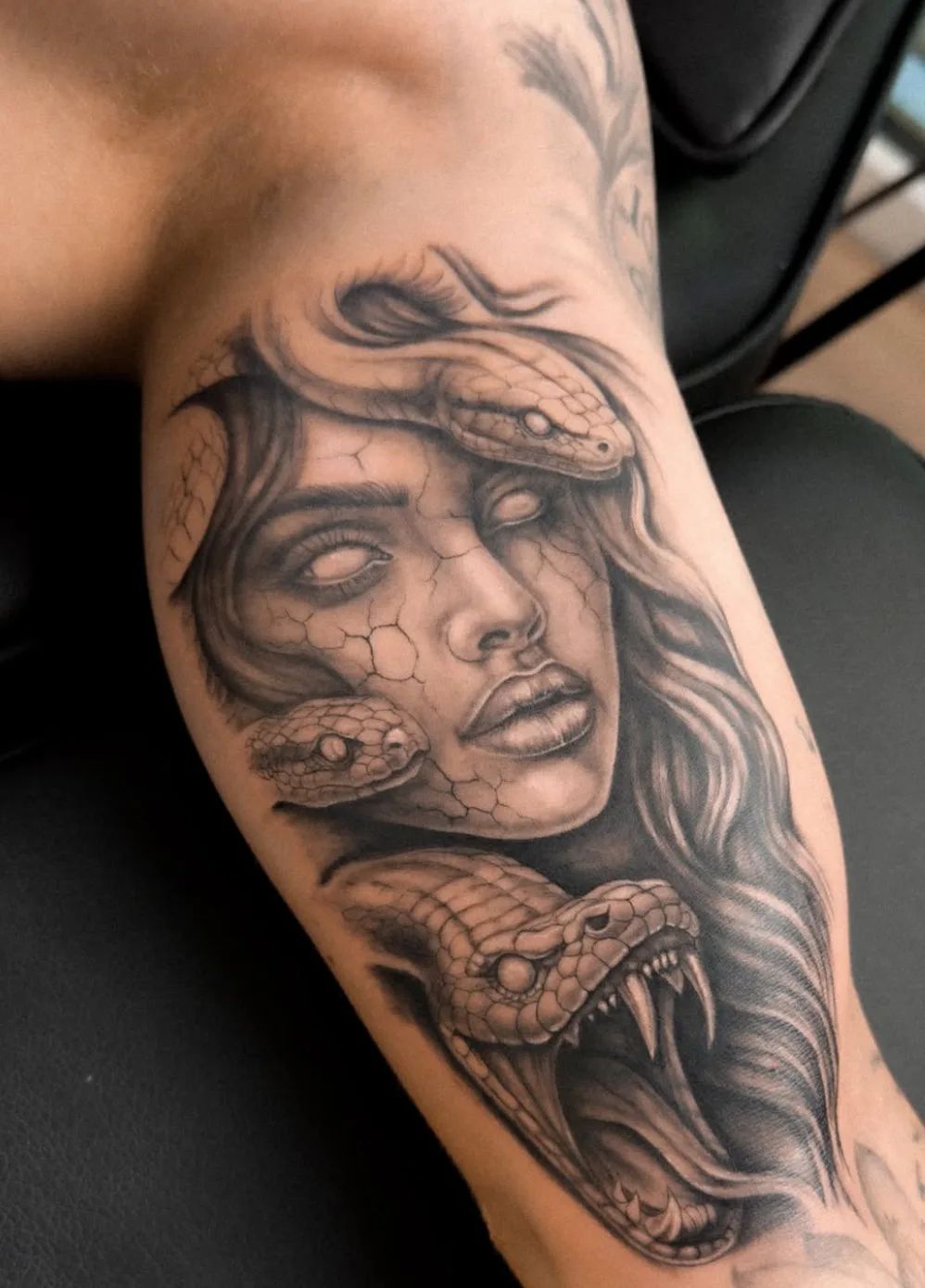 Realistisches Medusa Tattoo mit Schlangen und rissiger Haut am Oberarm