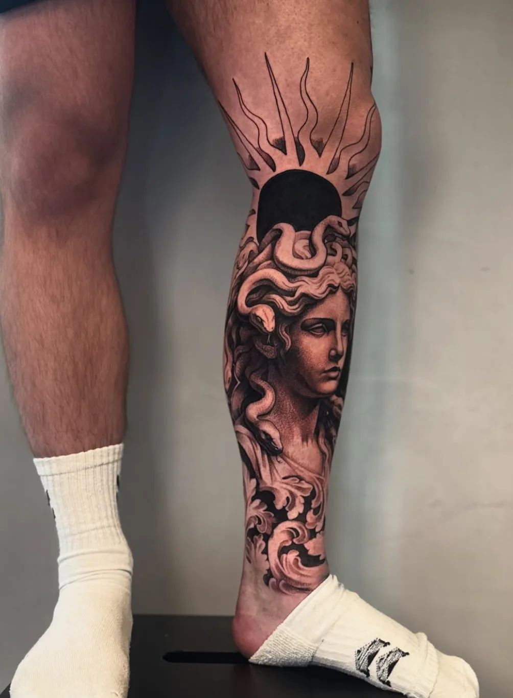 Realistisches Medusa Tattoo mit Sonne und Ornamenten am Schienbein