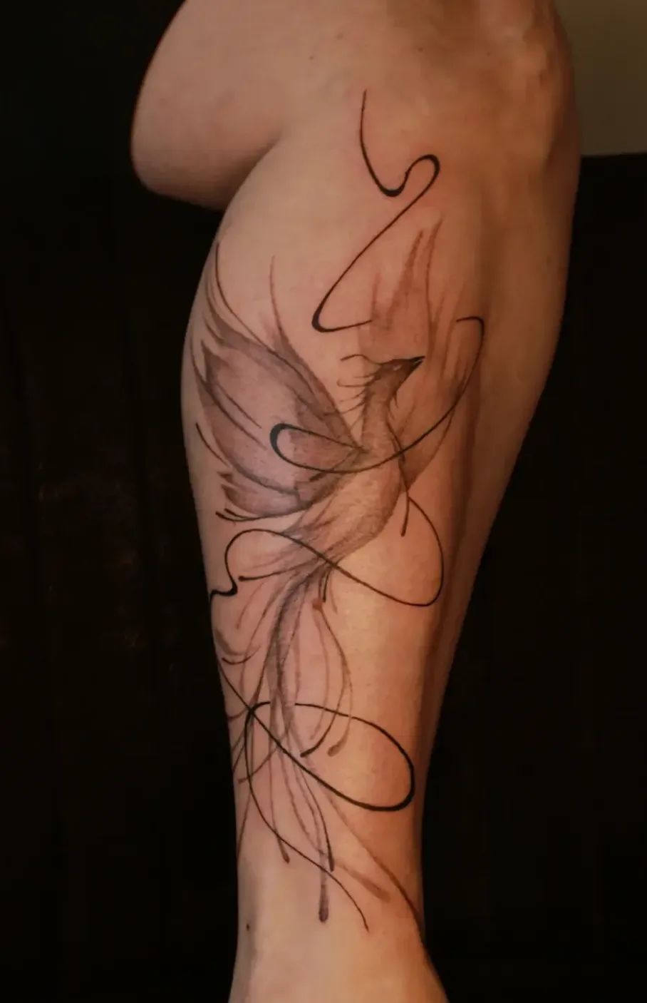 Watercolor phoenix tattoo with fine line accents on the leg
