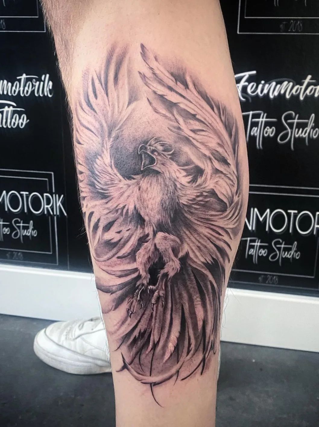 Realistic black and grey phoenix tattoo on leg