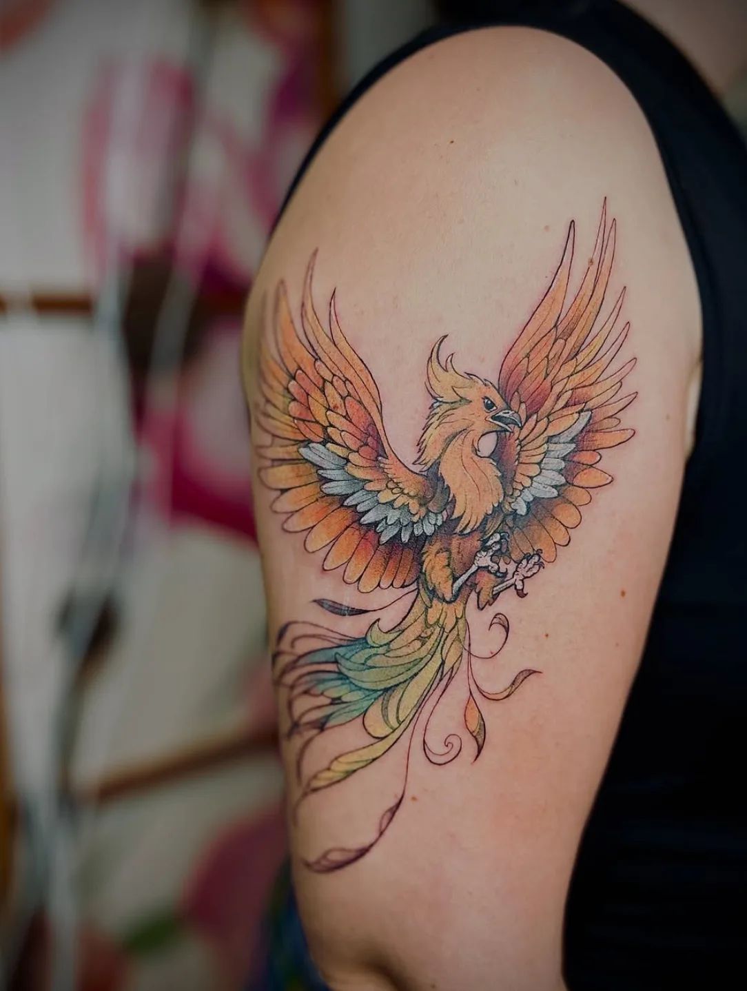 Colorful phoenix tattoo in fineline style on the upper arm