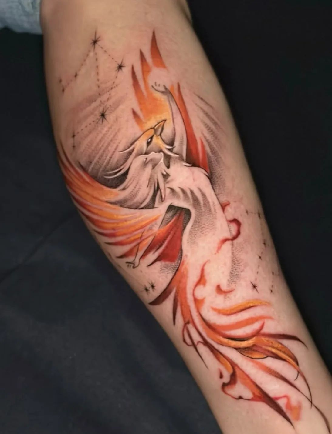 Phoenix tattoo in dotwork and fineline with stars and flames on forearm