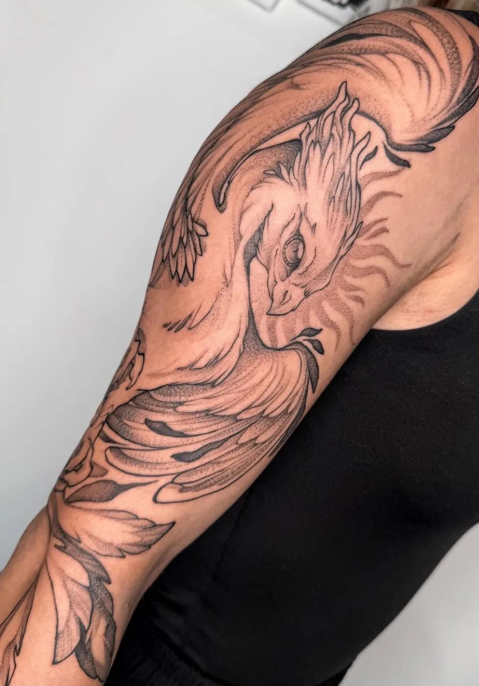 Phoenix tattoo in fine line style with dotwork on the upper arm