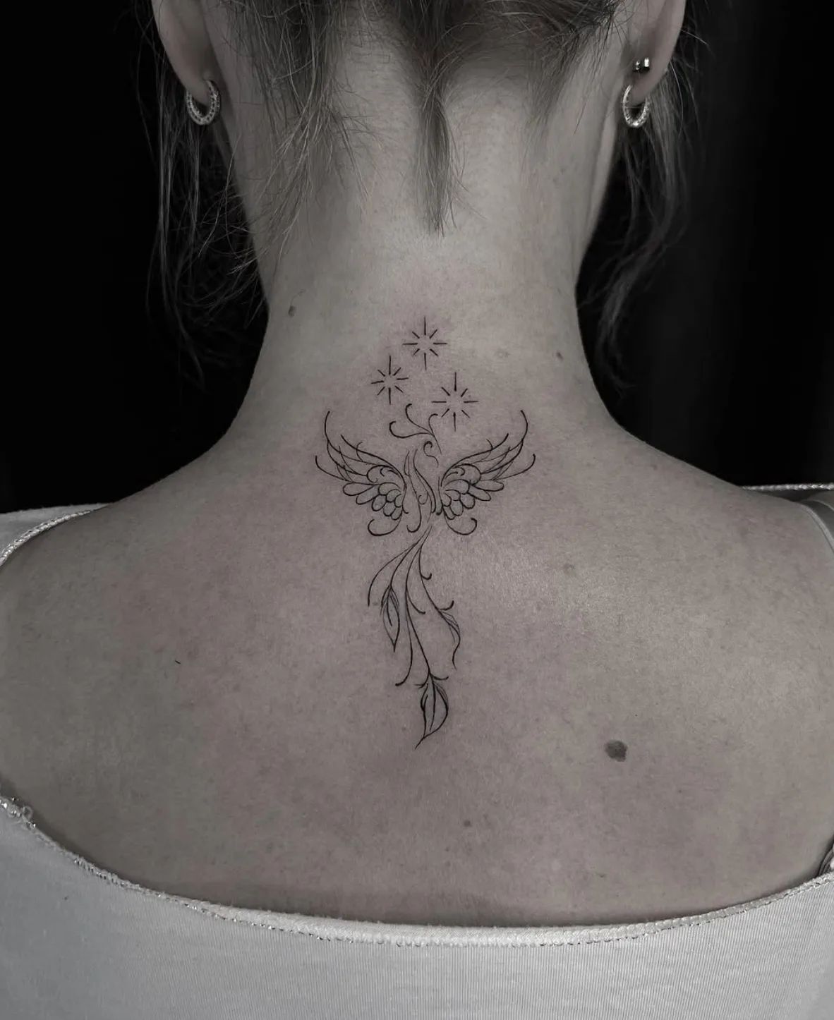 Fine line phoenix tattoo with stars on the neck