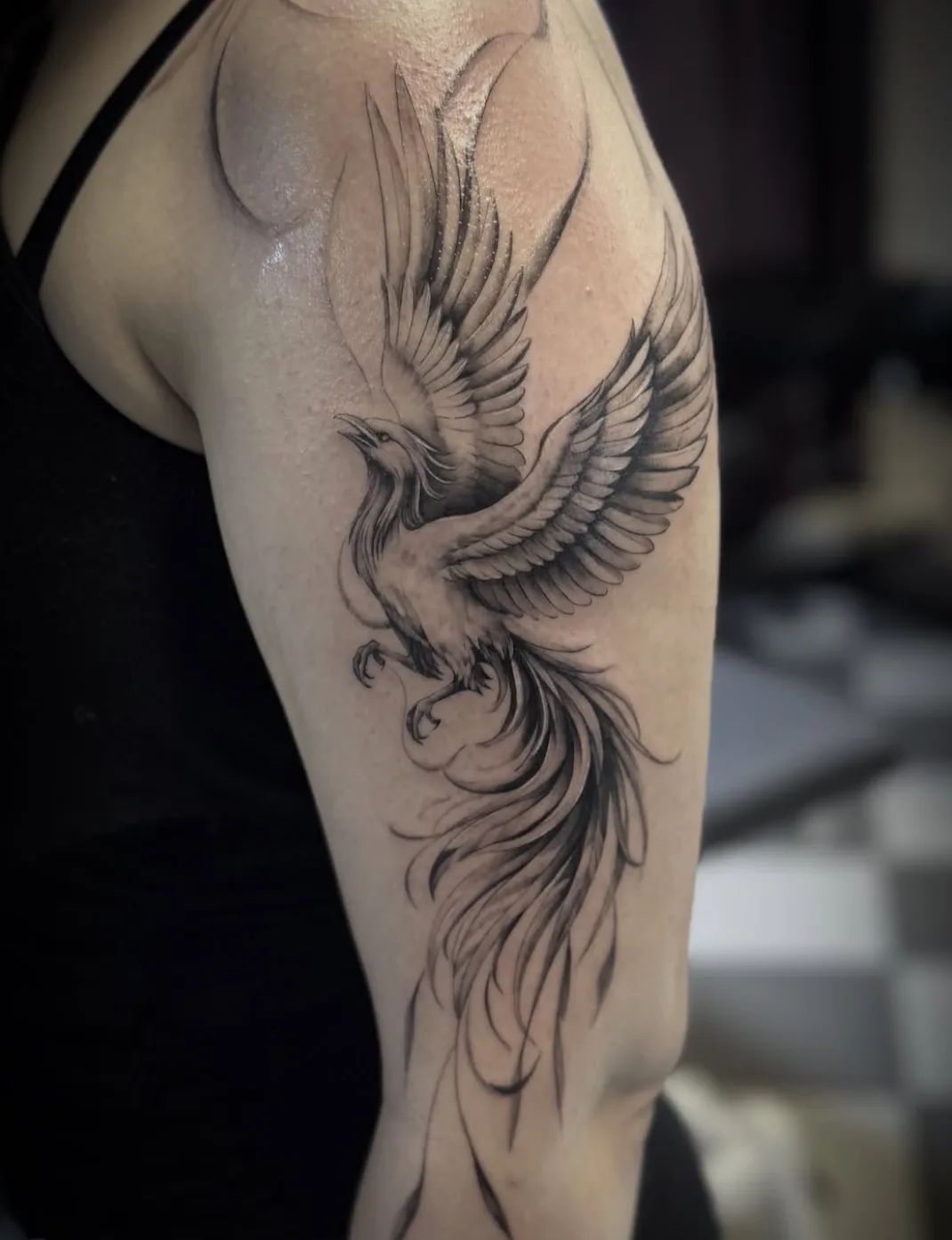 Fine line phoenix tattoo on upper arm