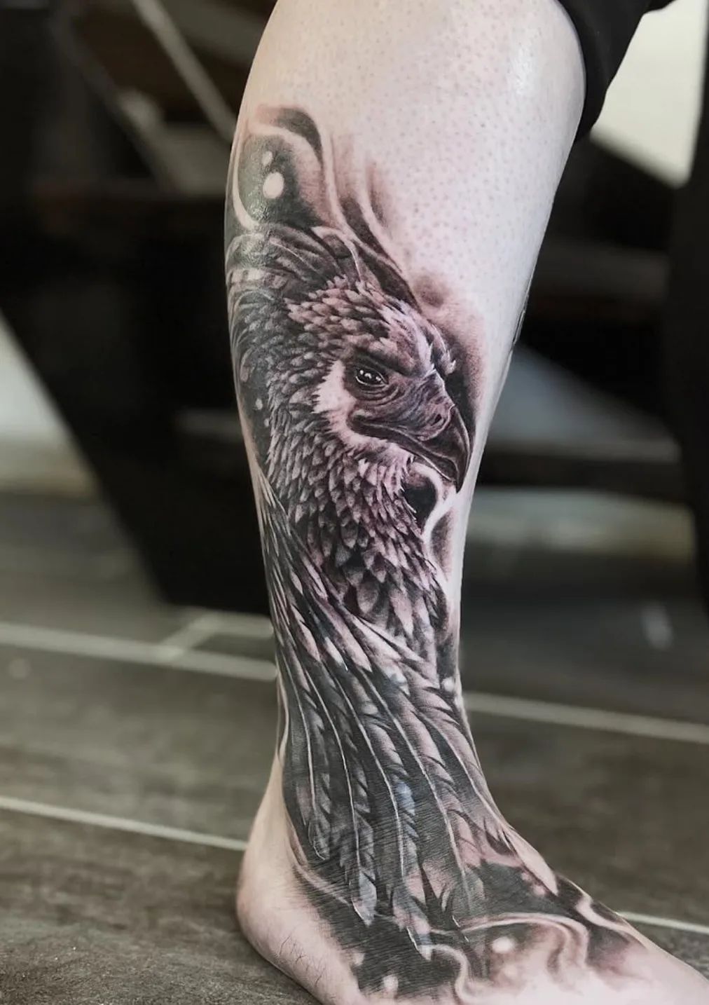 Realistic black and grey phoenix tattoo on lower leg and foot