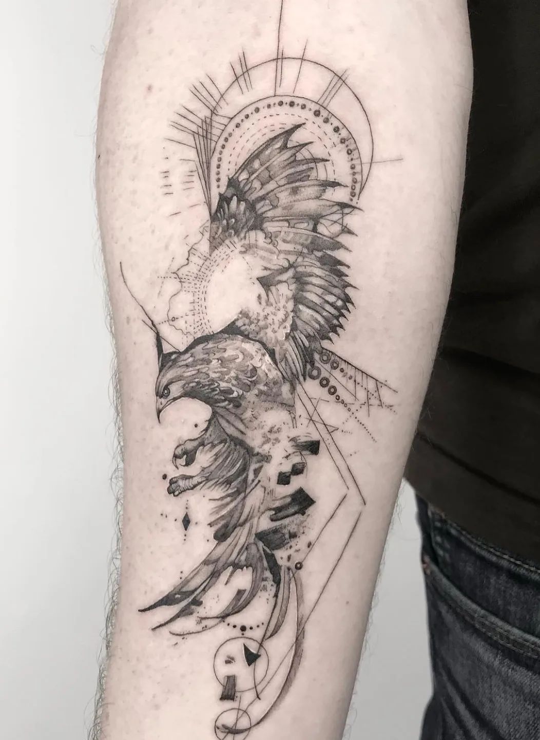 Fine line phoenix tattoo with geometric elements on forearm