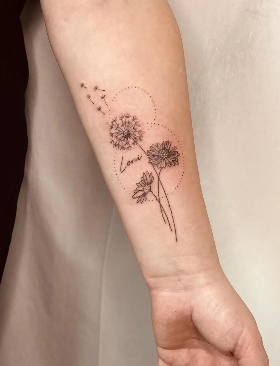 Dandelion and daisy fine line tattoo with lettering on forearm