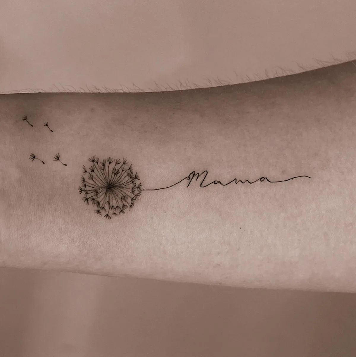 Dandelion tattoo with Mama lettering in fine line style on forearm