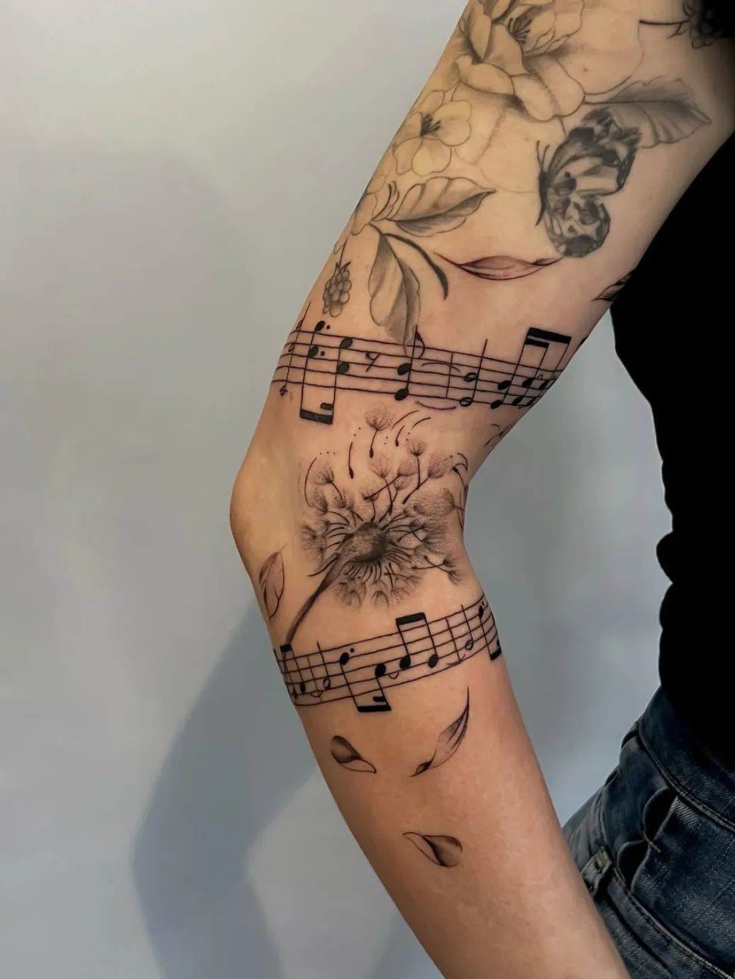 Dandelion tattoo with musical notes band and butterfly in fineline on upper arm