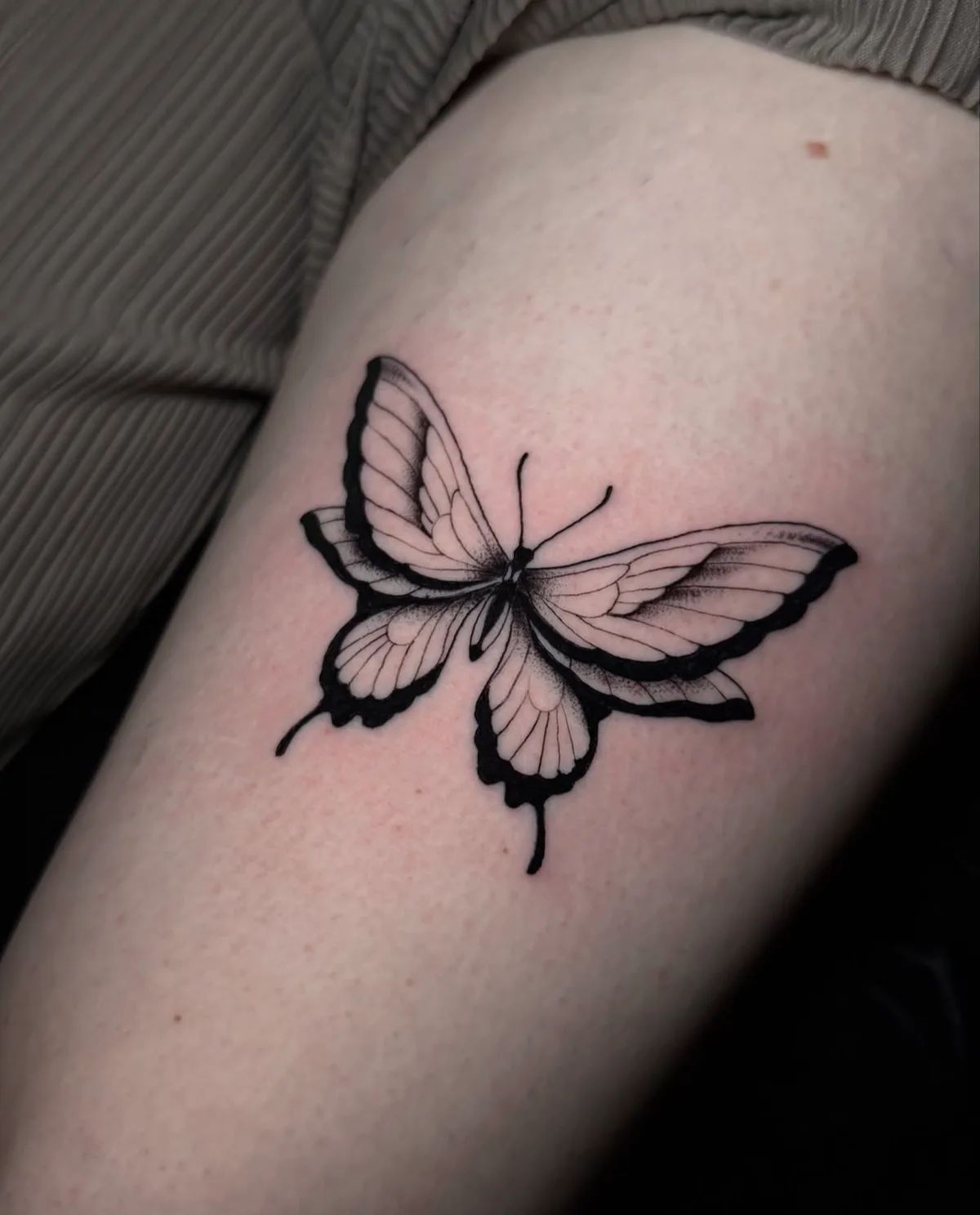 Schmetterling Tattoo im Fineline-Stil am Oberarm