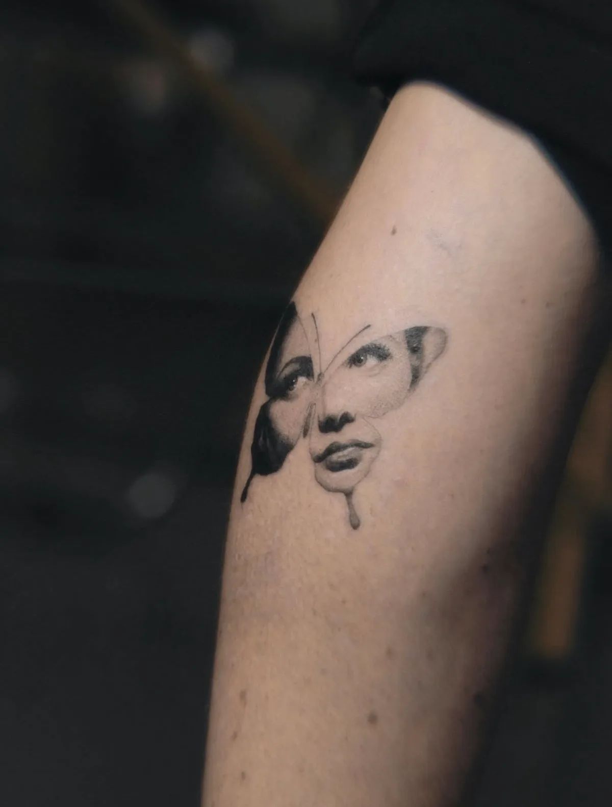 Schmetterling Tattoo mit Frauengesicht im Surrealismus-Stil am Oberarm
