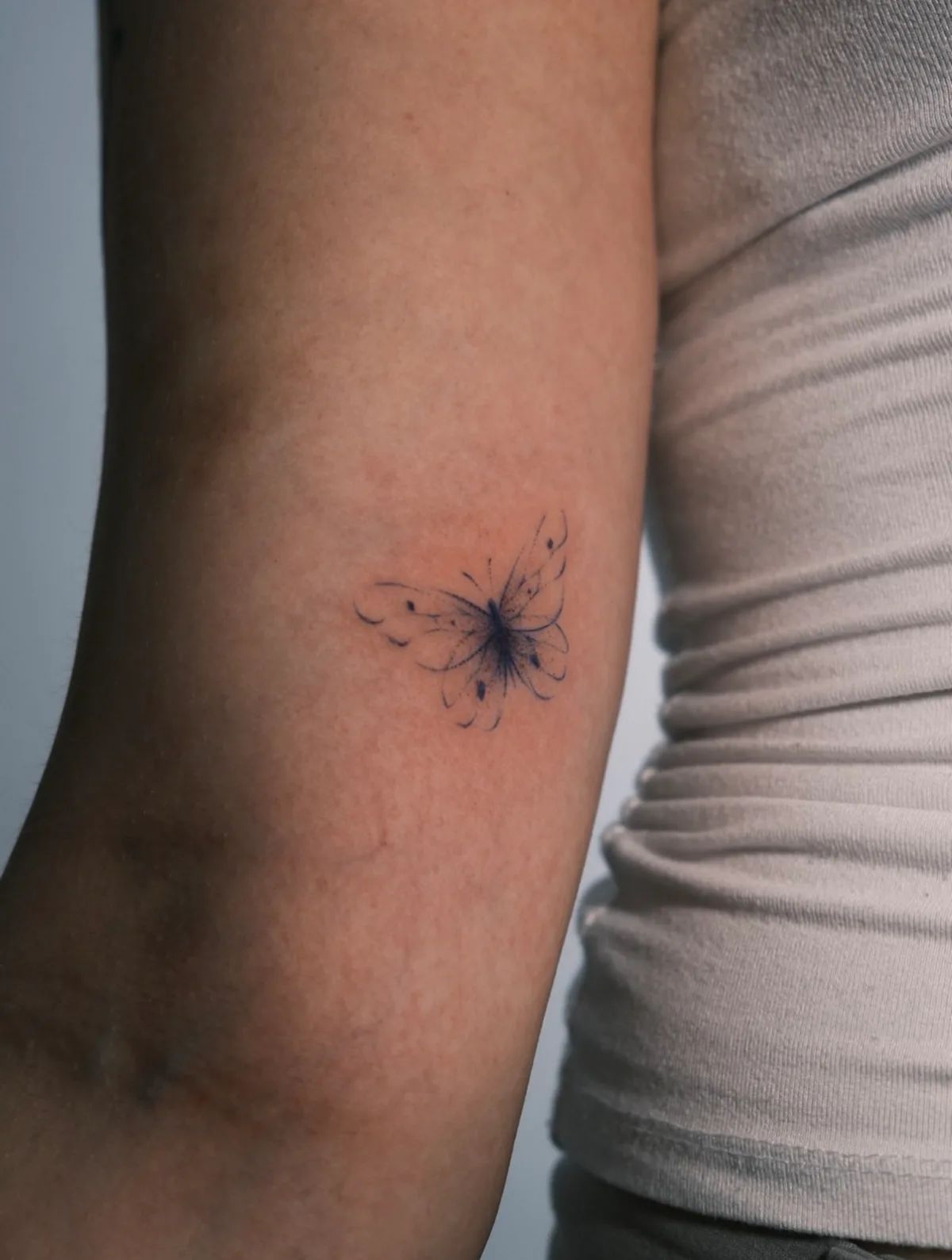Schmetterling Tattoo Fineline am Oberarm