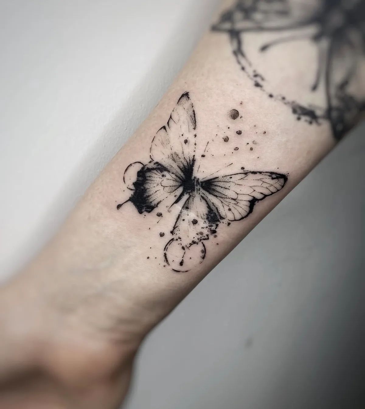 Abstraktes Schmetterling Tattoo im Trash Polka Stil am Unterarm